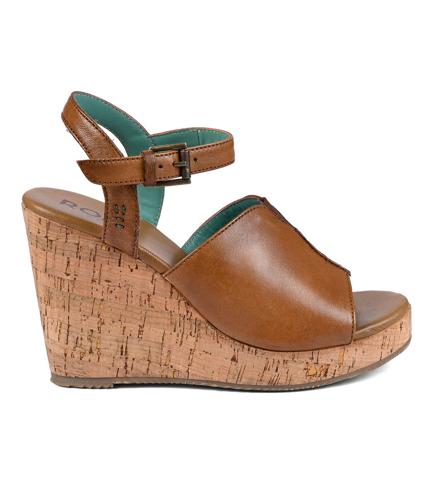 
                  
                    Brown full-grain leather Deduction wedge sandal with a cork platform and buckle strap, isolated on a white background by Roan.
                  
                