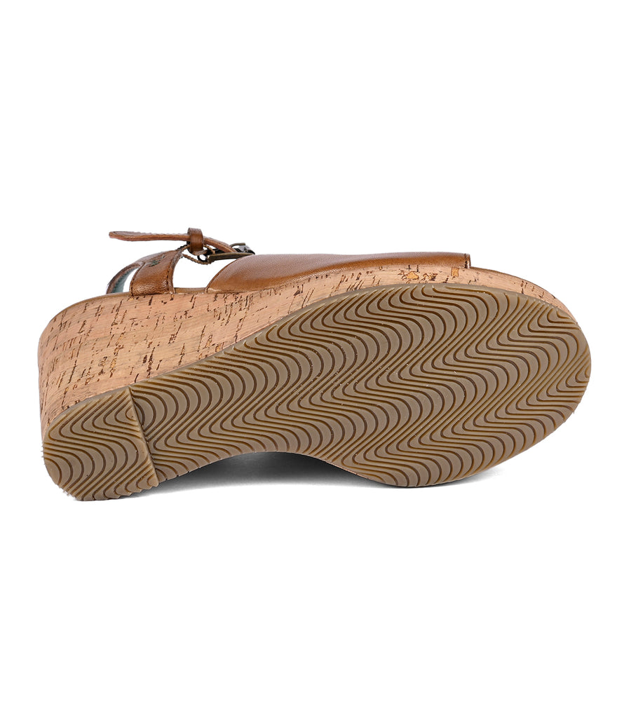 
                  
                    Bottom view of a brown full-grain leather Deduction sandal with an ankle strap and a cork wedge sole featuring a wavy tread pattern by Roan.
                  
                