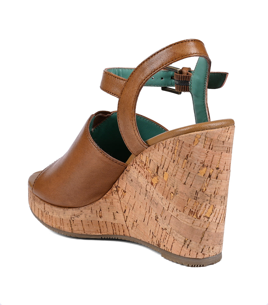 
                  
                    A brown full-grain leather Deduction wedge sandal with a cork heel and a green ankle strap, isolated on a white background.
                  
                