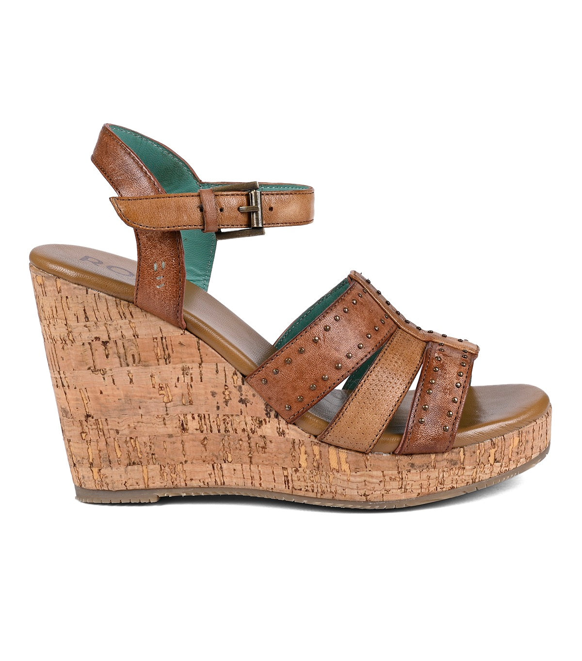 
                  
                    Brown full-grain leather wedge sandal with cork platform and studded straps by Roan, isolated on a white background.
                  
                
