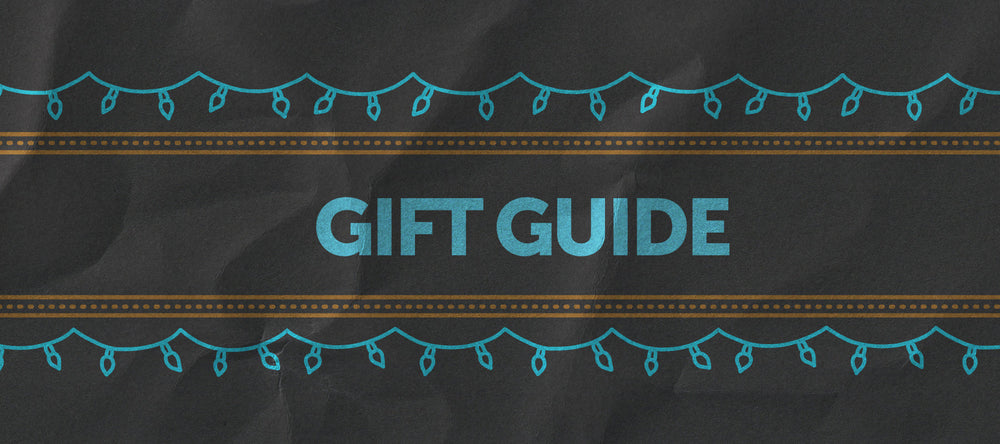 A beige background with blue ornaments hanging above a blue-outlined rectangle containing the words "GIFT GUIDE" in bold, capital letters.
