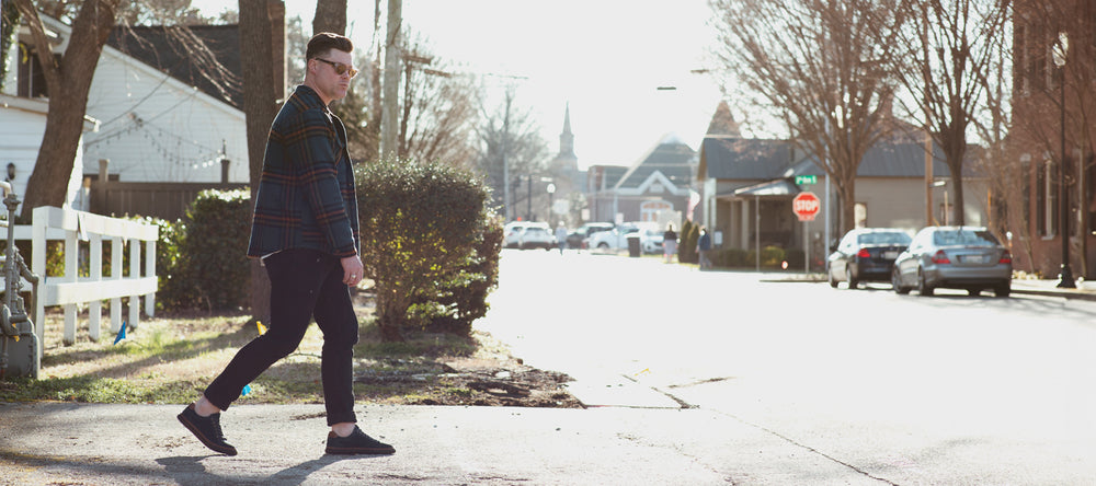 Man walking across a residential street on a sunny day.
