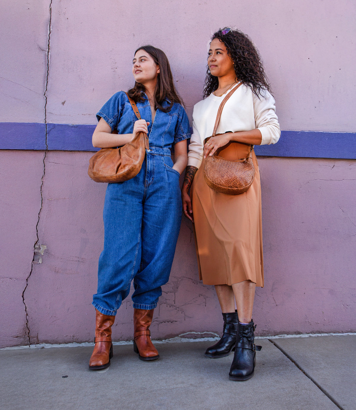 
                  
                    Two women stand against a pink wall, each carrying the Roan Trickle bag—one pairs it with a blue jumpsuit and brown boots, the other with a beige skirt, white top, and black boots—highlighting its everyday versatility.
                  
                
