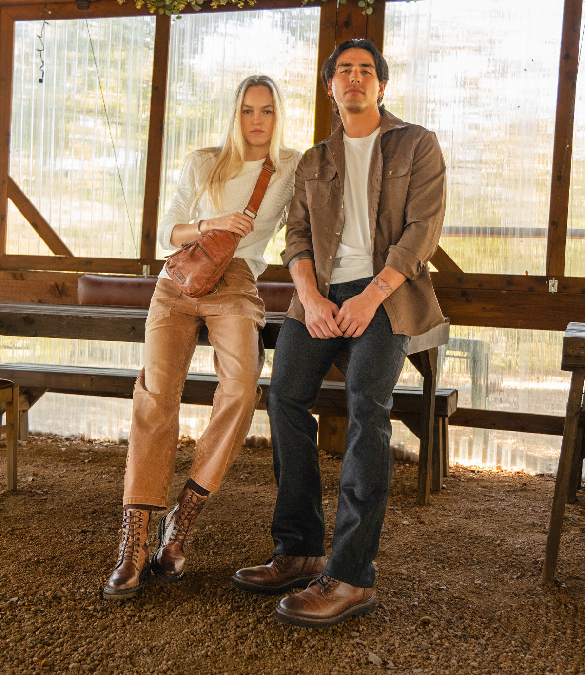 
                  
                    A woman and a man sit in a sunlit wooden space, both in casual earth-toned outfits, styled with leather shoes and Roan's Trickle—a compact leather bag that adds versatile flair to their everyday look.
                  
                