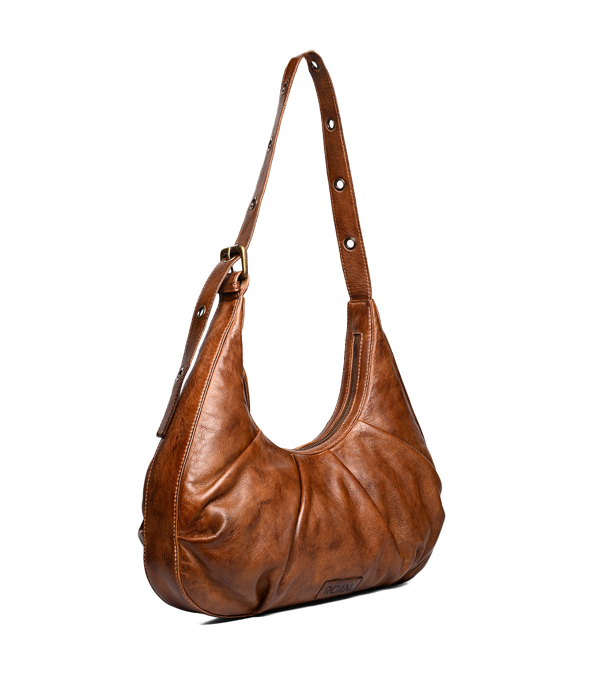 
                  
                    The Roan Behalf is a brown lambskin leather bag with a crescent silhouette, adjustable strap and buckle, silver grommet details, gathered design, and a visible brand tag at the bottom front.
                  
                