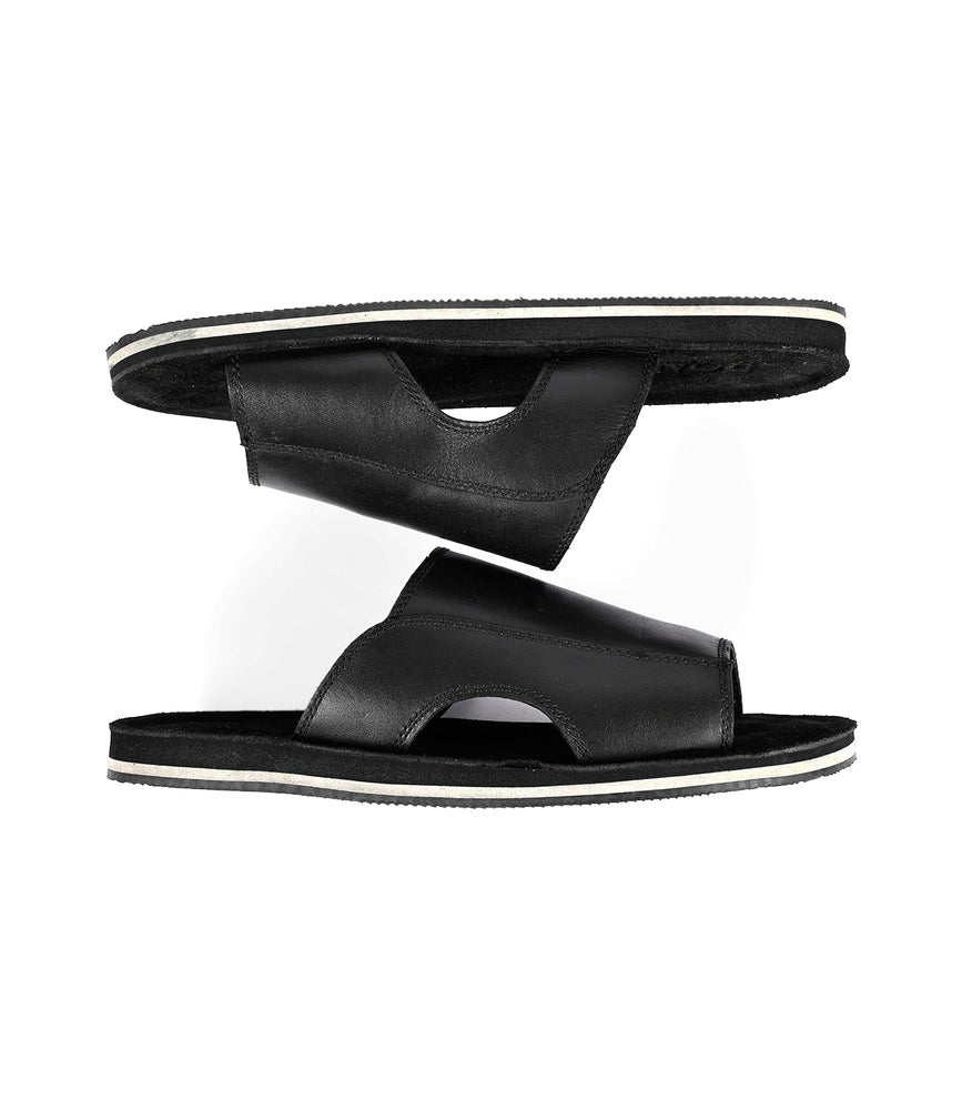 
                  
                    A pair of classic slip-on black Roan sandals stacked on top of each other against a white background.
                  
                