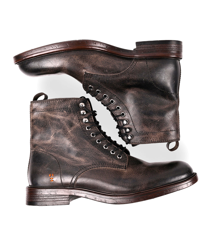 
                  
                    A pair of Roan Duty men's boots in dark brown, showing visible stitching and a worn texture with padded insoles, are displayed side by side against a white background.
                  
                
