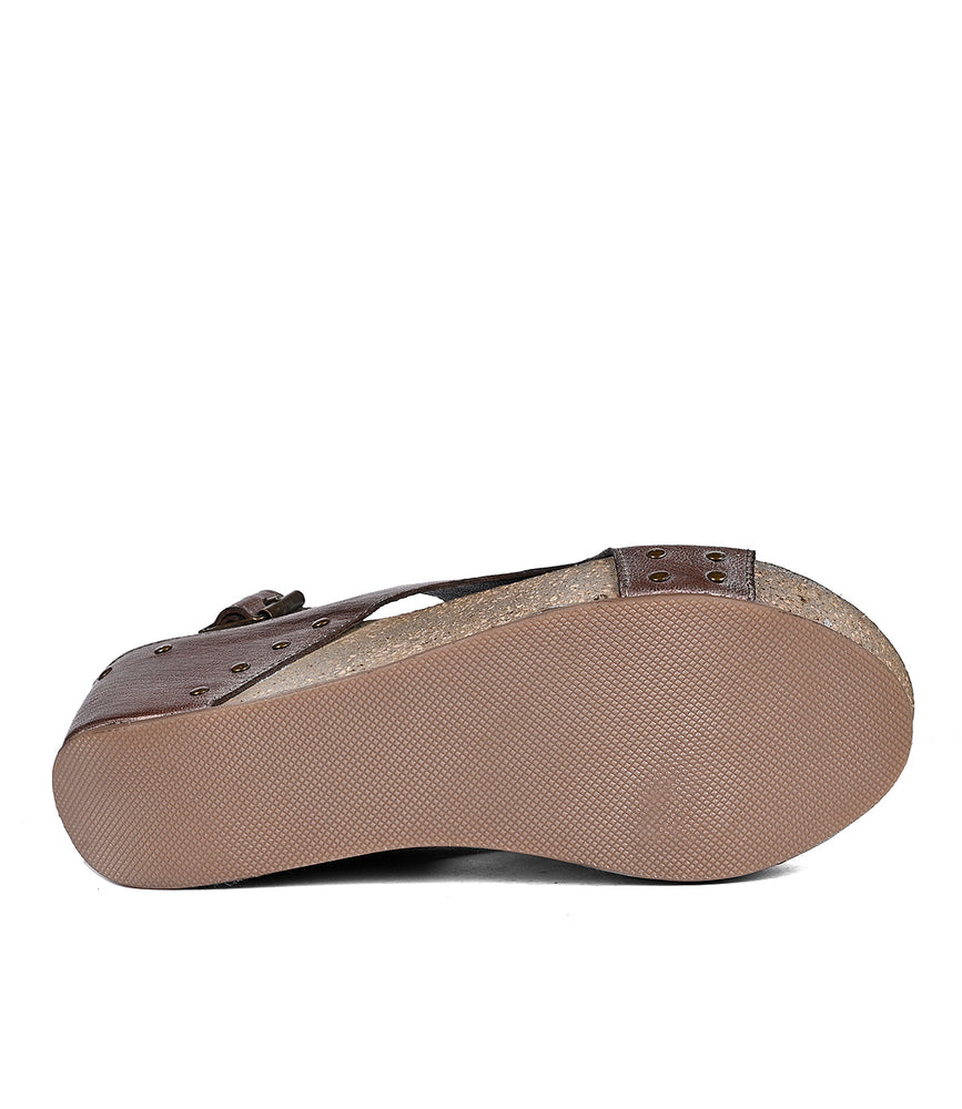 
                  
                    Side view of a brown full-grain leather Fortnight sandal with a cork footbed and adjustable buckle, against a white background by Roan.
                  
                