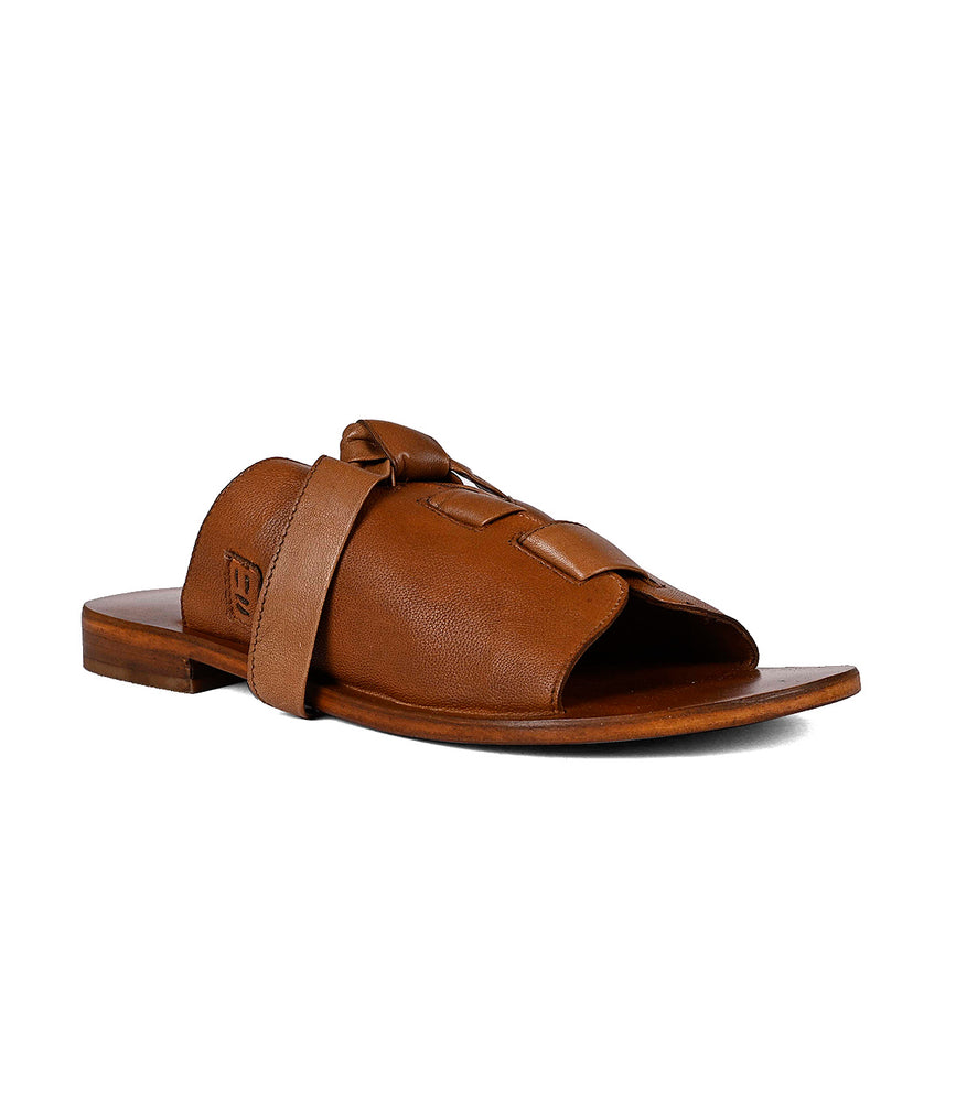 
                  
                    Brown leather slide sandal with adjustable leather straps on a white background by Roan Grapevine.
                  
                