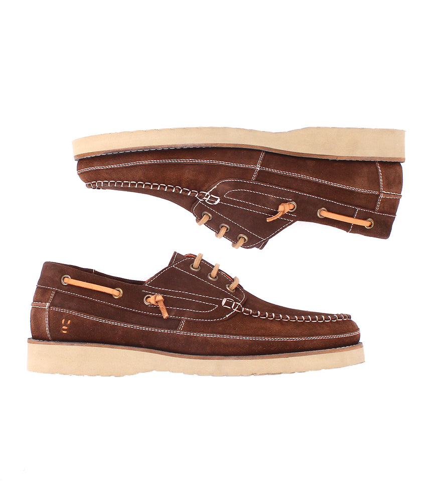 
                  
                    The Roan Glory is a pair of brown suede boat shoes with tan laces, beige stitching, cream rubber soles, and a cushioned footbed, shown from the side.
                  
                