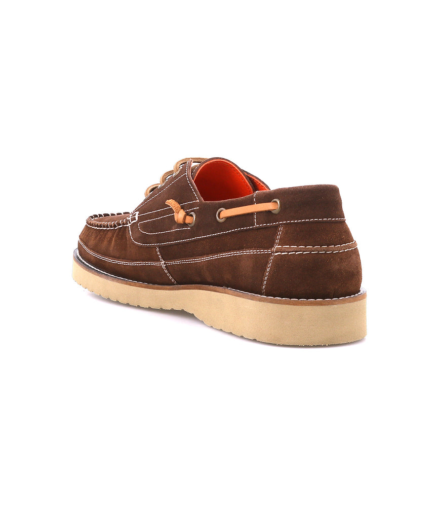 
                  
                    The Roan Glory is a brown suede boat shoe with nautical style, white stitching, tan laces, and a beige rubber sole, shown from the back angle.
                  
                