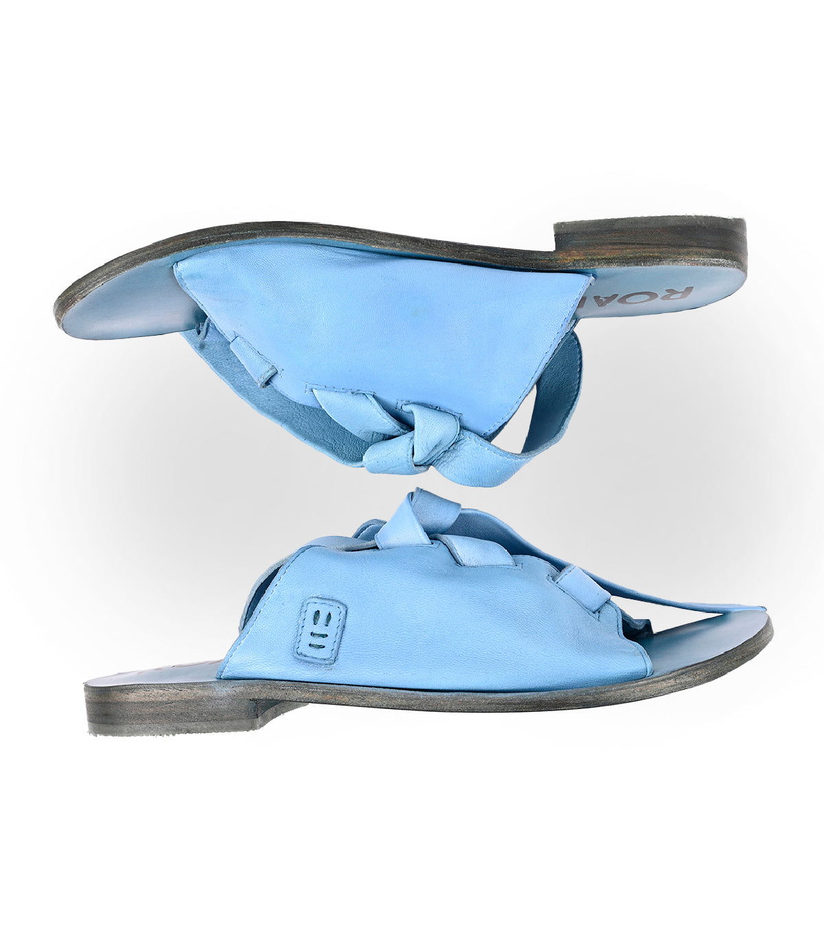 
                  
                    Roan’s Grapevine sandals in light blue feature open toes, knotted straps, and a leather outsole—luxurious footwear shown side by side on a white background.
                  
                