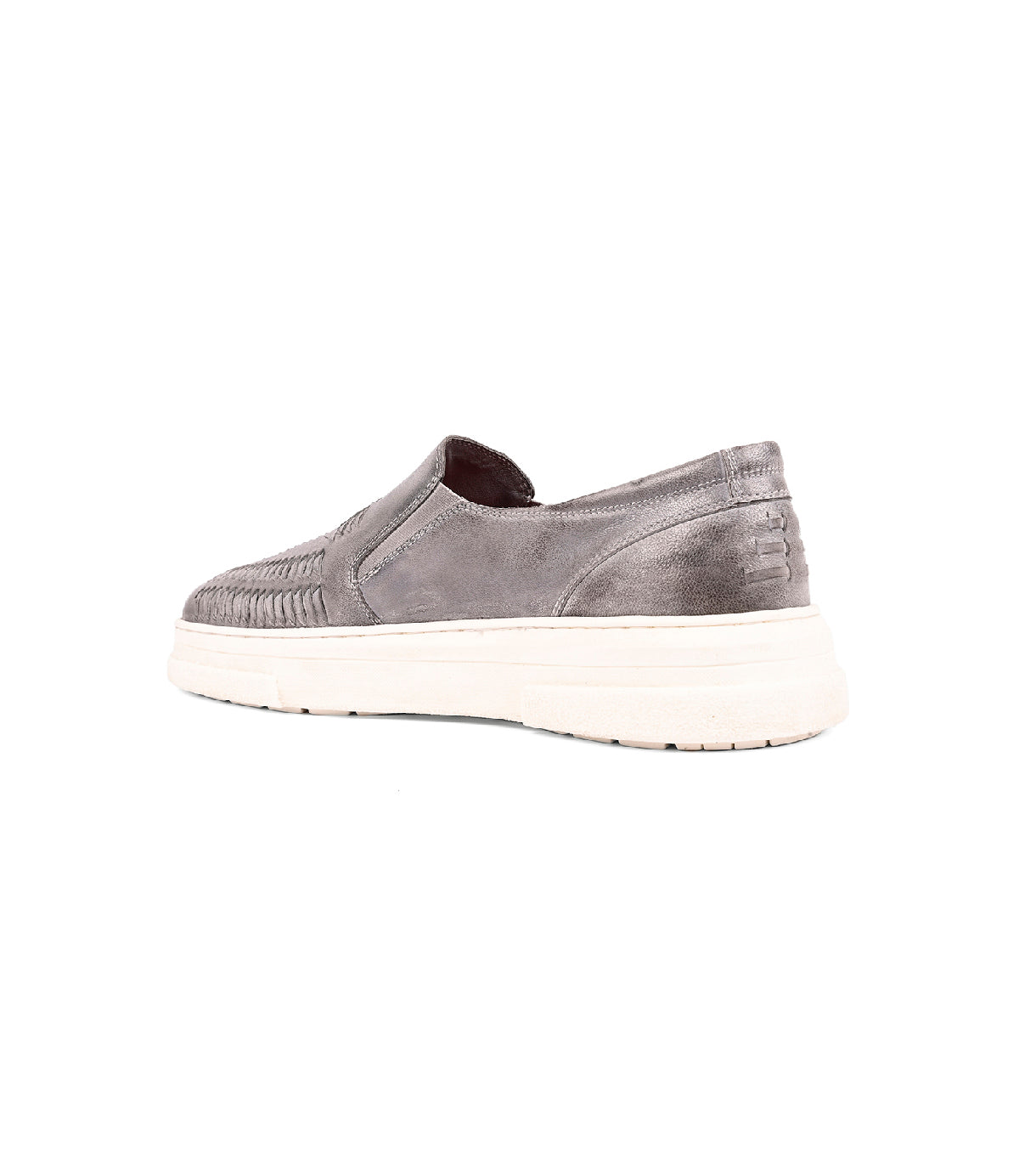 
                  
                    The Roan Gregor is a gray handwoven goat leather slip-on with a washed finish and white sole, shown at an angle to display its side and back, featuring woven detailing and visible stitching.
                  
                
