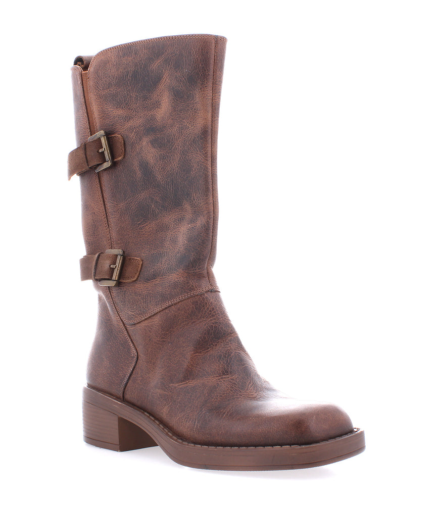 The Roan Iceberg is a mid-calf brown leather boot with a low block heel, two side buckles, and a textured, moto-inspired distressed finish.