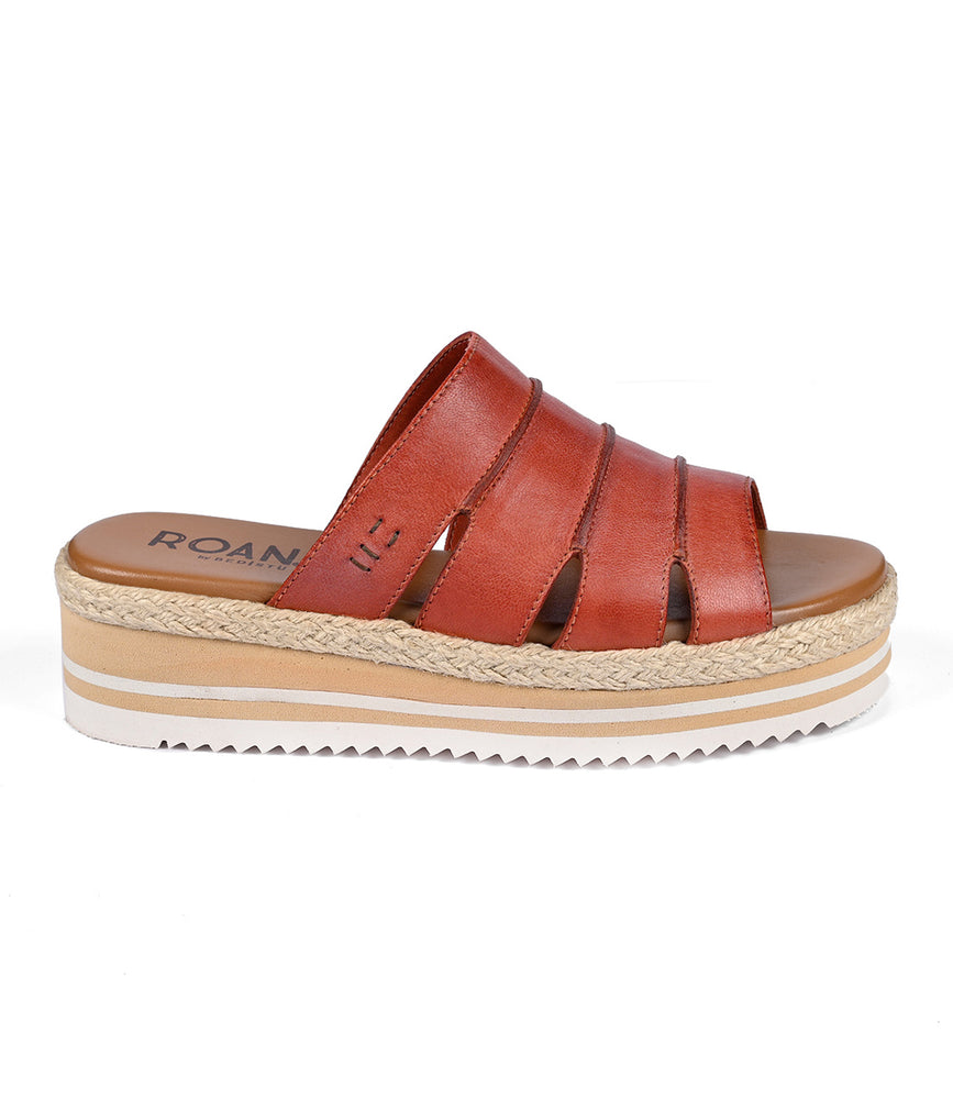 The Roan Incant is a brown leather sandal featuring a cushioned footbed, multi-strap design, and a platform sole with rope and white serrated rubber layers.