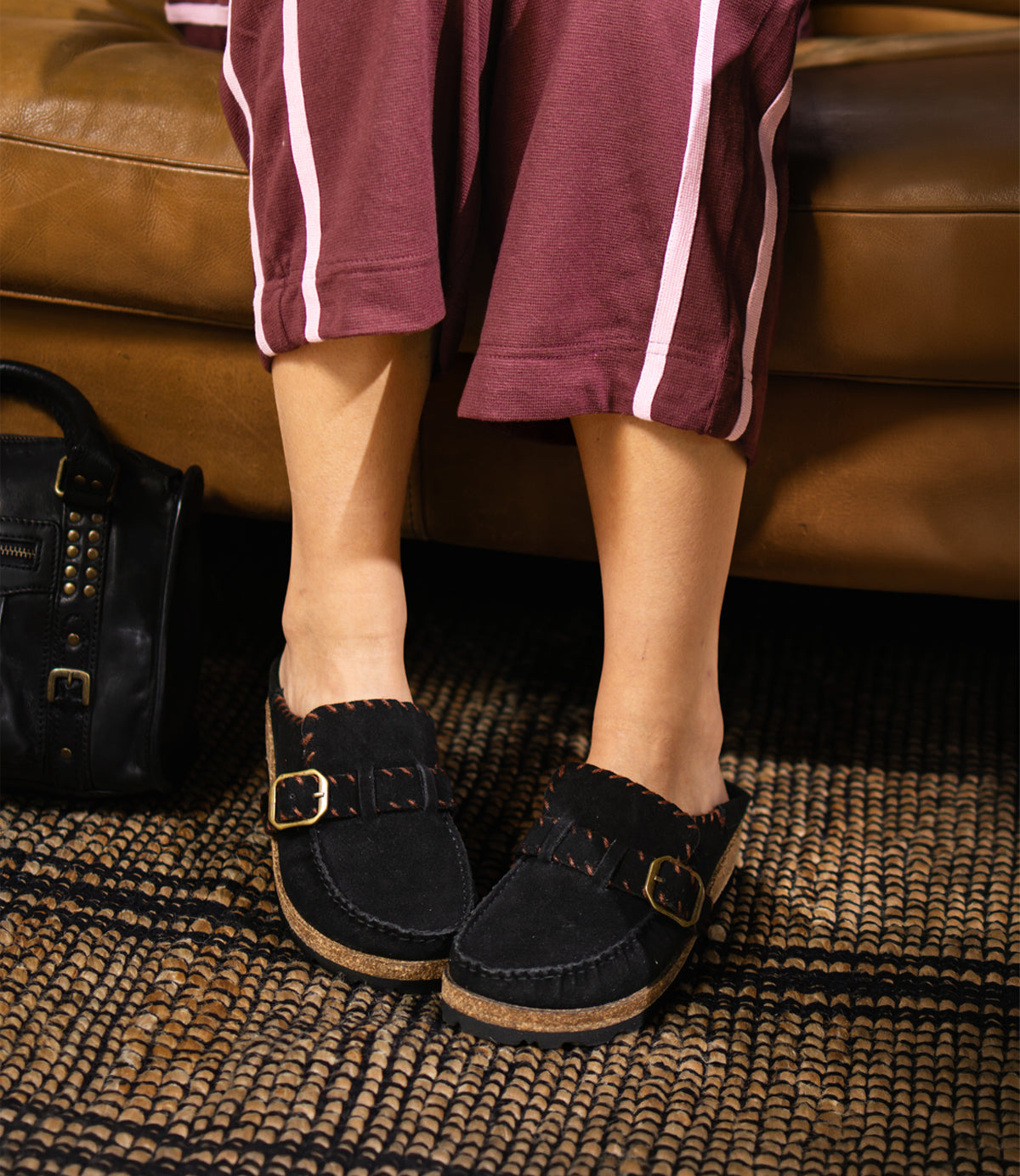 
                  
                    Roan Mingle black plush suede mule slip-ons with a gold-tone buckle and a thick, chunky cork-wrapped sole.
                  
                