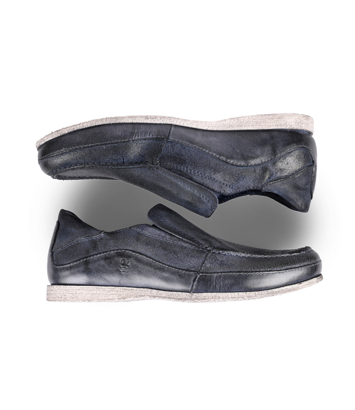 
                  
                    A pair of worn blue leather slip-on loafers (Shevon) arranged vertically on a white background.
                  
                