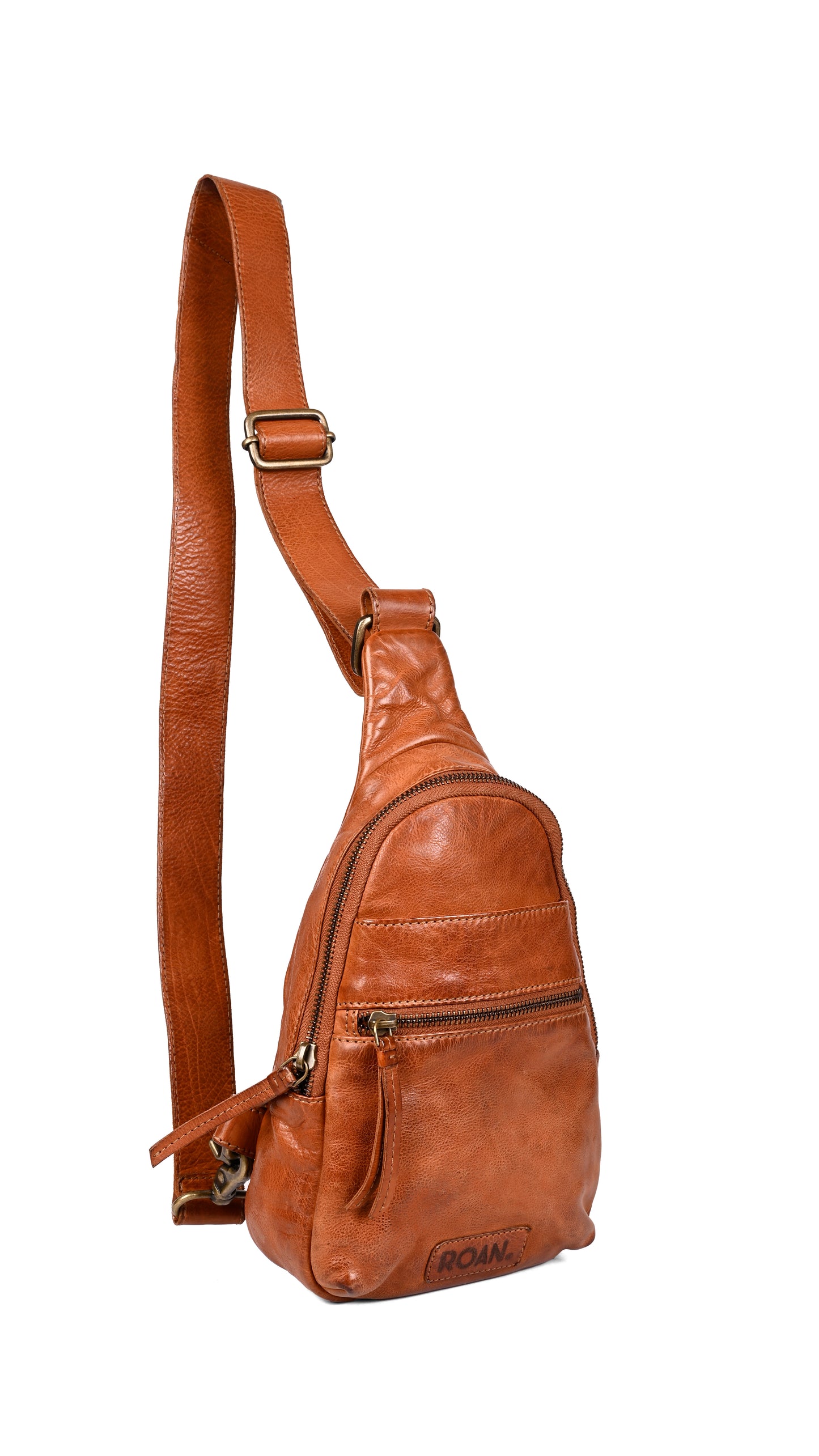 
                  
                    The Roan Trickle is a brown leather sling bag with adjustable strap and multiple zippered pockets for everyday versatility, shown against a white background.
                  
                
