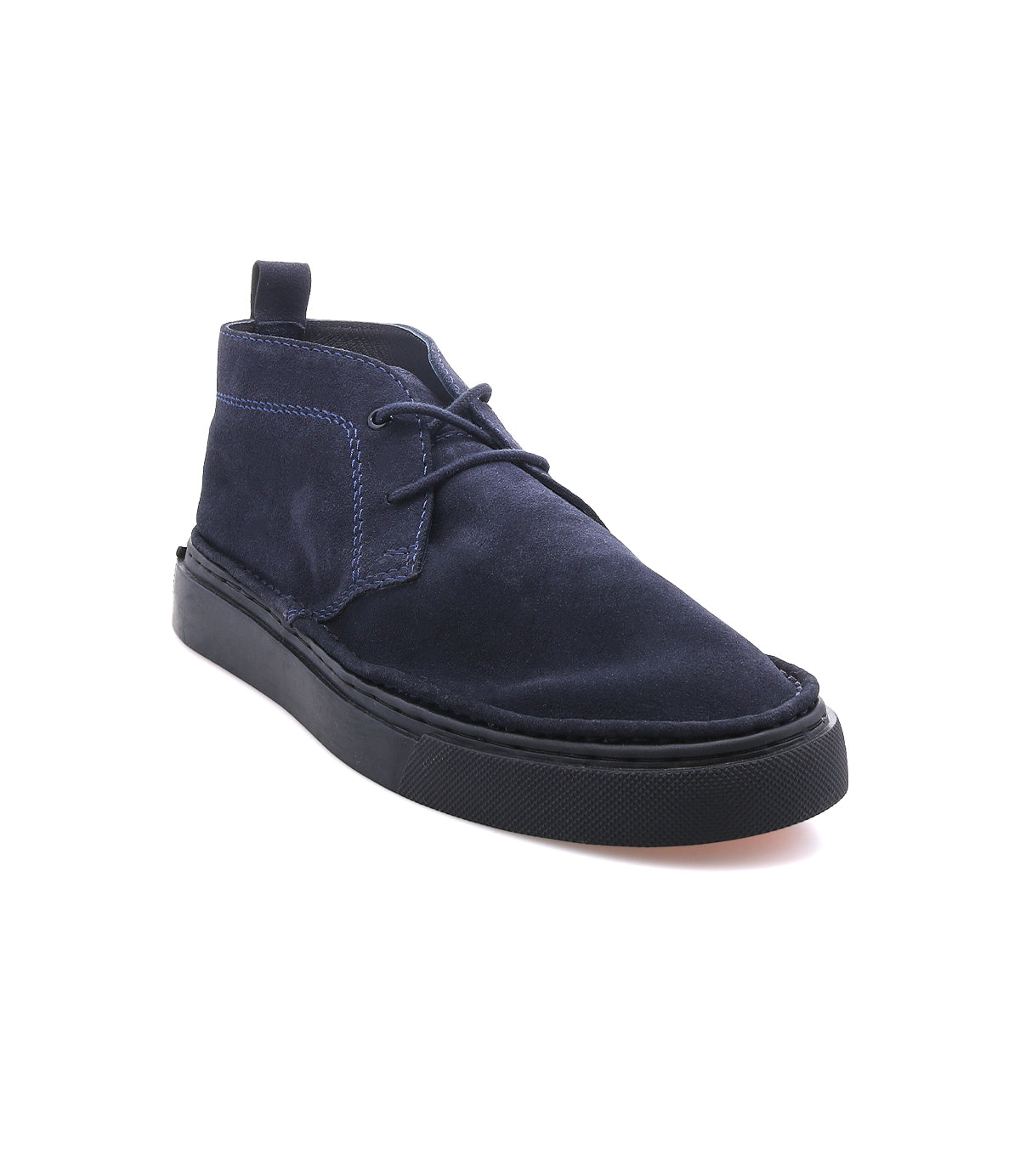 
                  
                    The Roan Volunteer is a navy blue suede chukka boot with black laces and a sneaker-style sole, shown against a white background.
                  
                