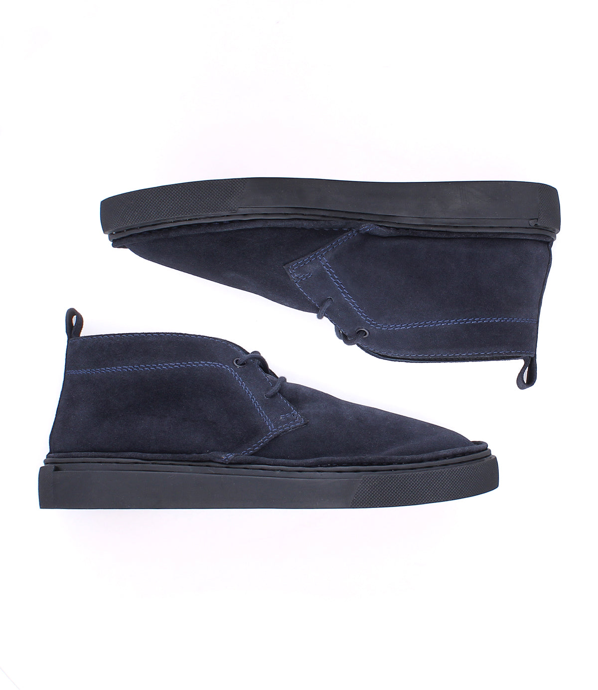
                  
                    A pair of Roan Volunteer chukka boots in navy blue suede, featuring black sneaker-style soles and a handy heel pull tab, displayed from the side on a white background.
                  
                