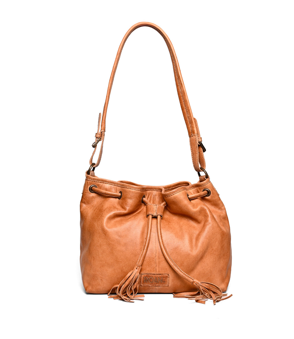 
                  
                    The Roan Zone is a light brown cow suede leather bucket bag with a drawstring closure, adjustable strap, and tassel accents, shown on a plain white background.
                  
                