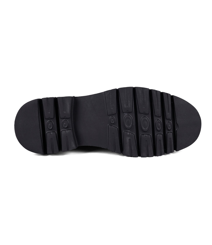 
                  
                    A black boot sole featuring a rugged, traction-friendly tread pattern is displayed against a white background, showcasing the meticulous hand-finishing process characteristic of Roan's Defy Chelsea boots.
                  
                