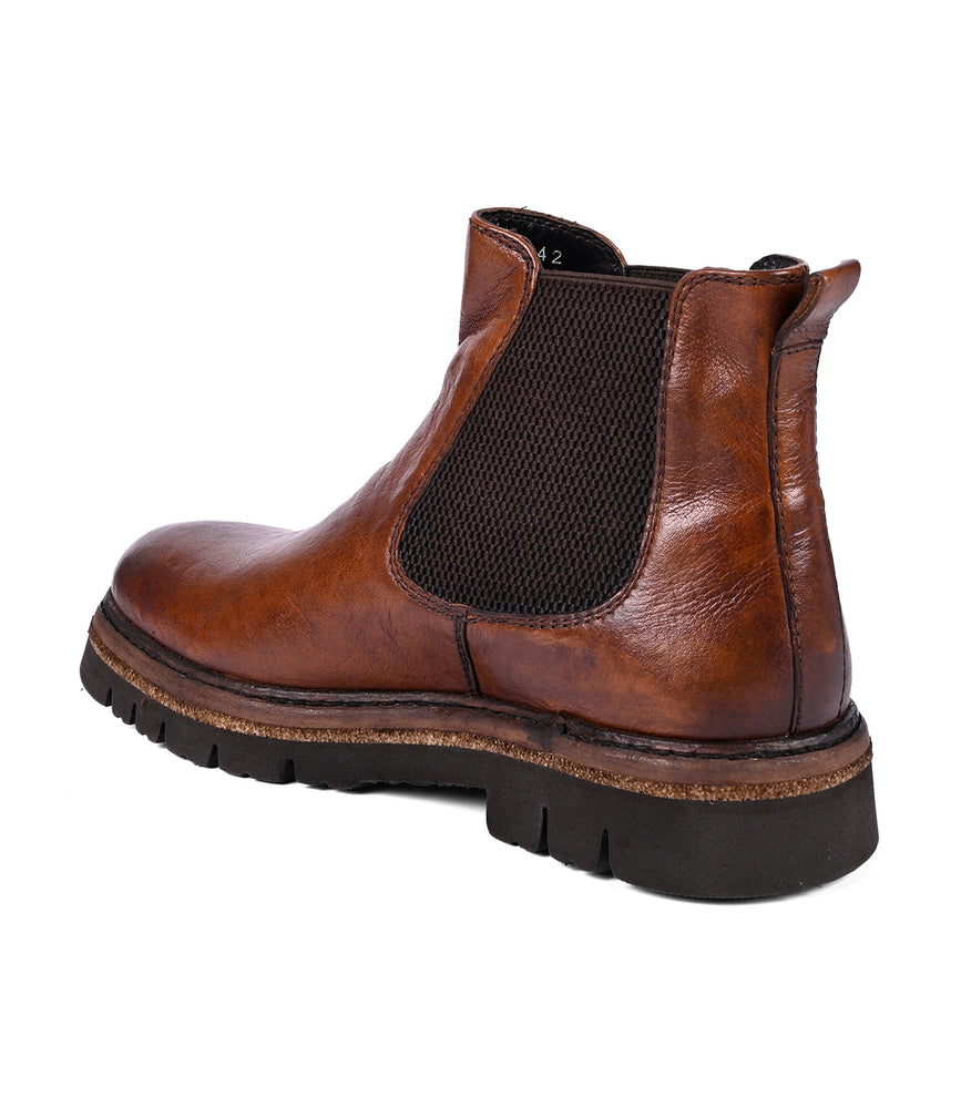 
                  
                    The Defy boots by Roan feature a black elastic side panel and a traction-friendly rubber sole in brown leather, showcasing exquisite hand-finishing details.
                  
                