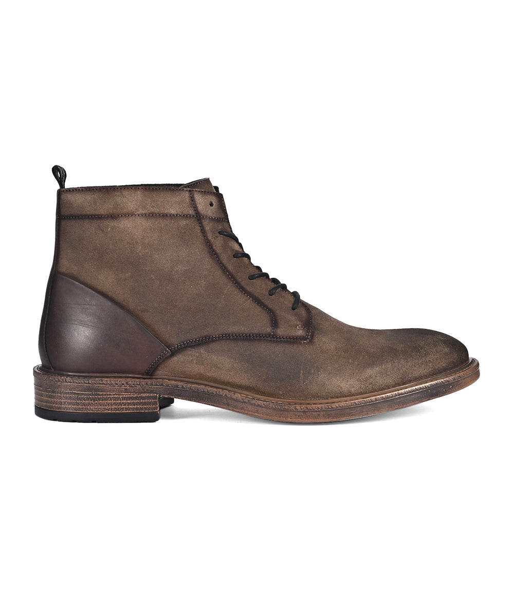 The Joyride by Roan is a brown full-grain leather ankle boot featuring a textured surface, lace-up front, and stacked heel.